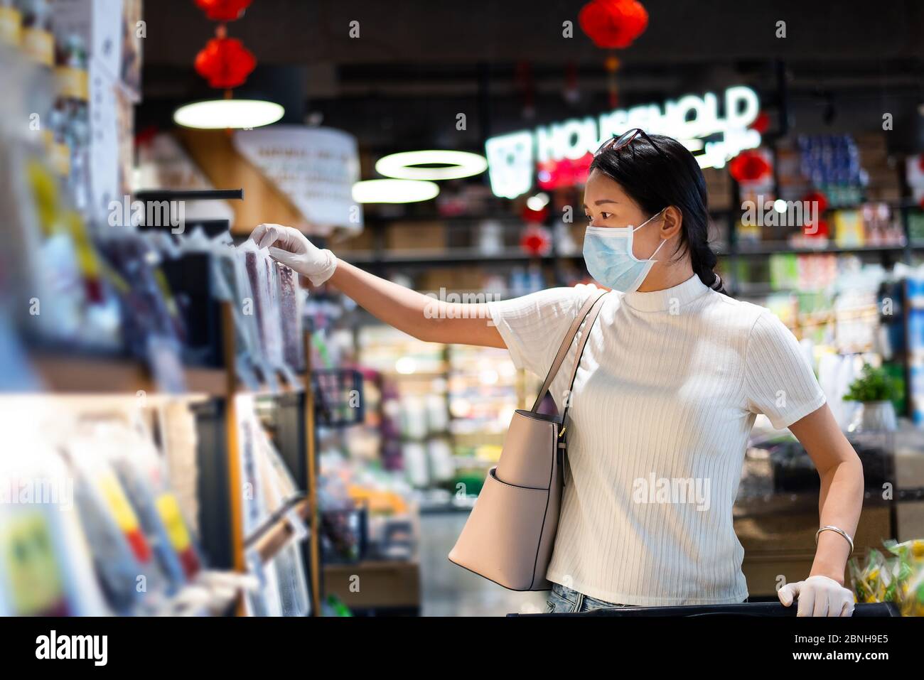 Asiatische Frau, die auf dem Markt Lebensmittel kauft, trägt Maske und Handschuhe, um die Ausbreitung von Virius während der Coronavirus-Pandemie zu verhindern Stockfoto