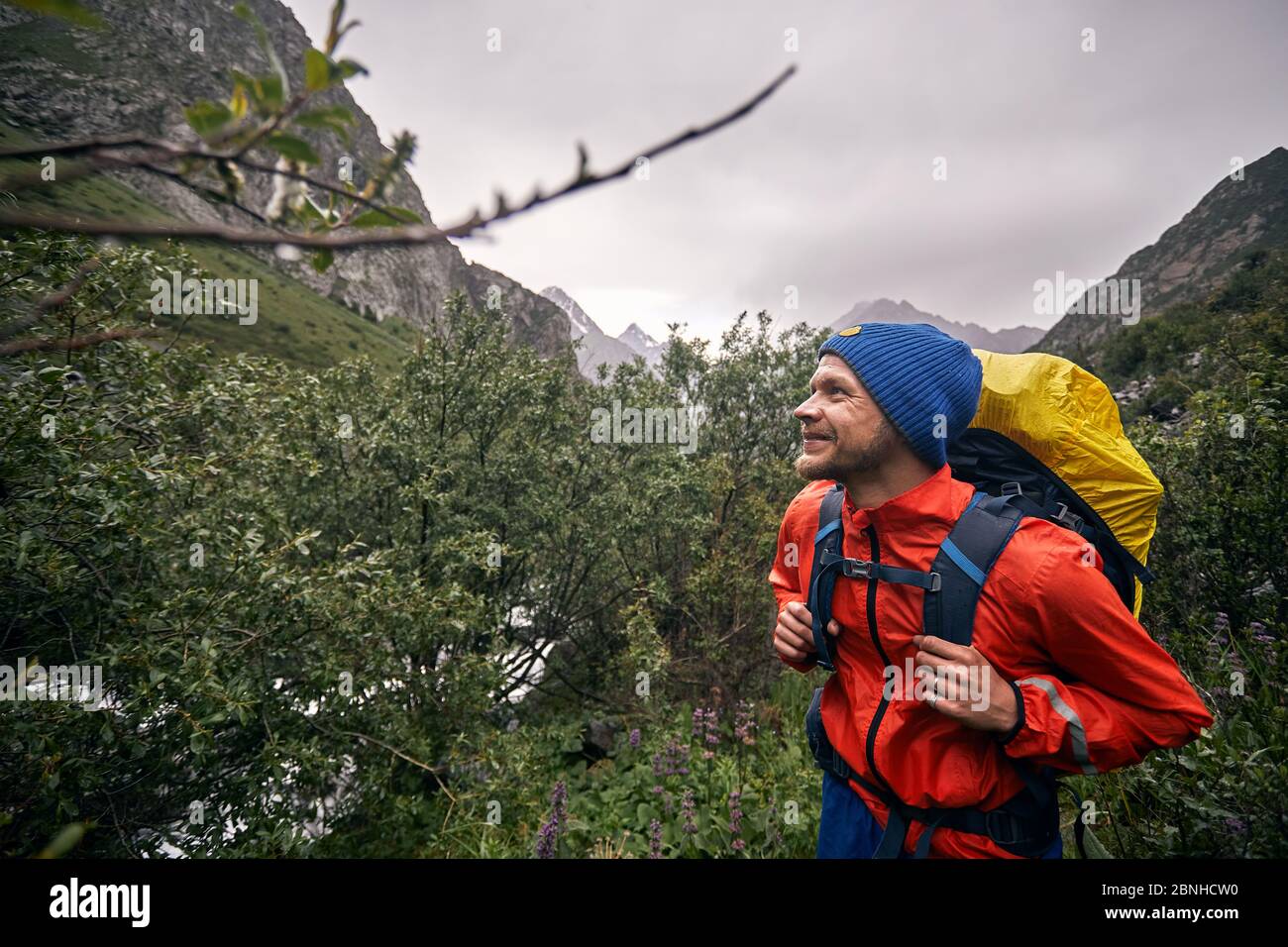 Porträt des glücklichen Touristen mit großem Rucksack ist im Bergtal des Karakol-Nationalparks, Kirgisistan Stockfoto