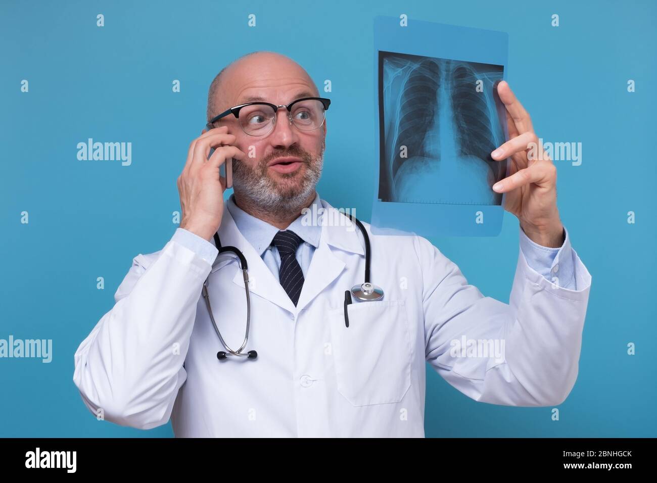 Arzt hält eine Röntgenaufnahme des Brustkorbs und spricht am Telefon Mit Patient Stockfoto