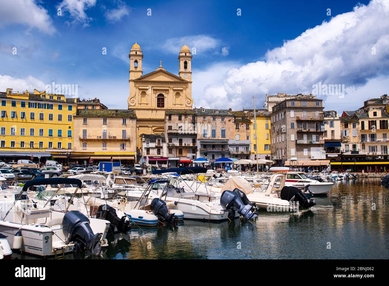 Sehen Sie sich die église Saint Jean-Baptiste in Bastia vom vieux Hafen aus an, während der Sommermonate einige Boote im Hafen ruhen Stockfoto