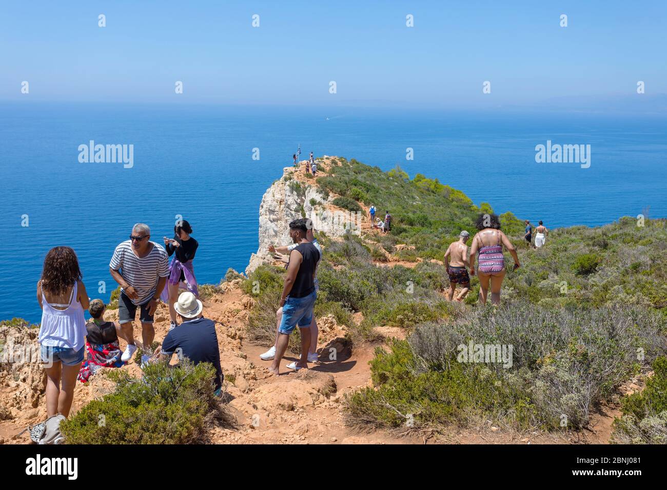 ZAKYNTHOS, GRIECHENLAND - 21. JULI 2018: Touristen gehen an einer rauen Klippe, um Fotos von dem berühmten Strand mit einem alten Schiffswrack auf der Insel Zakynthos zu machen Stockfoto