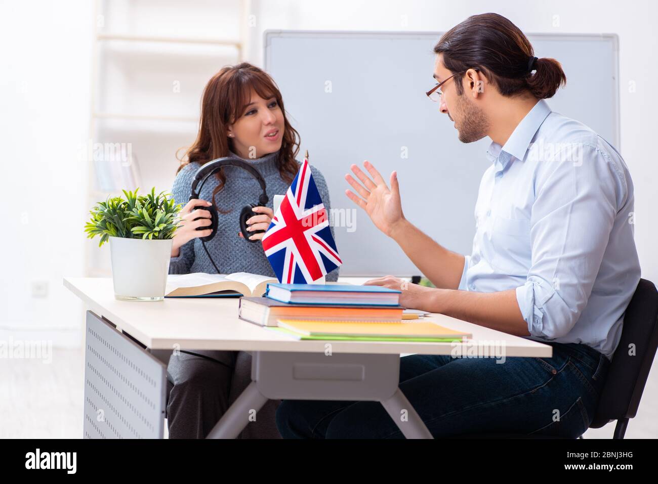 Junger Schüler und männlicher englischlehrer im Klassenzimmer Stockfoto