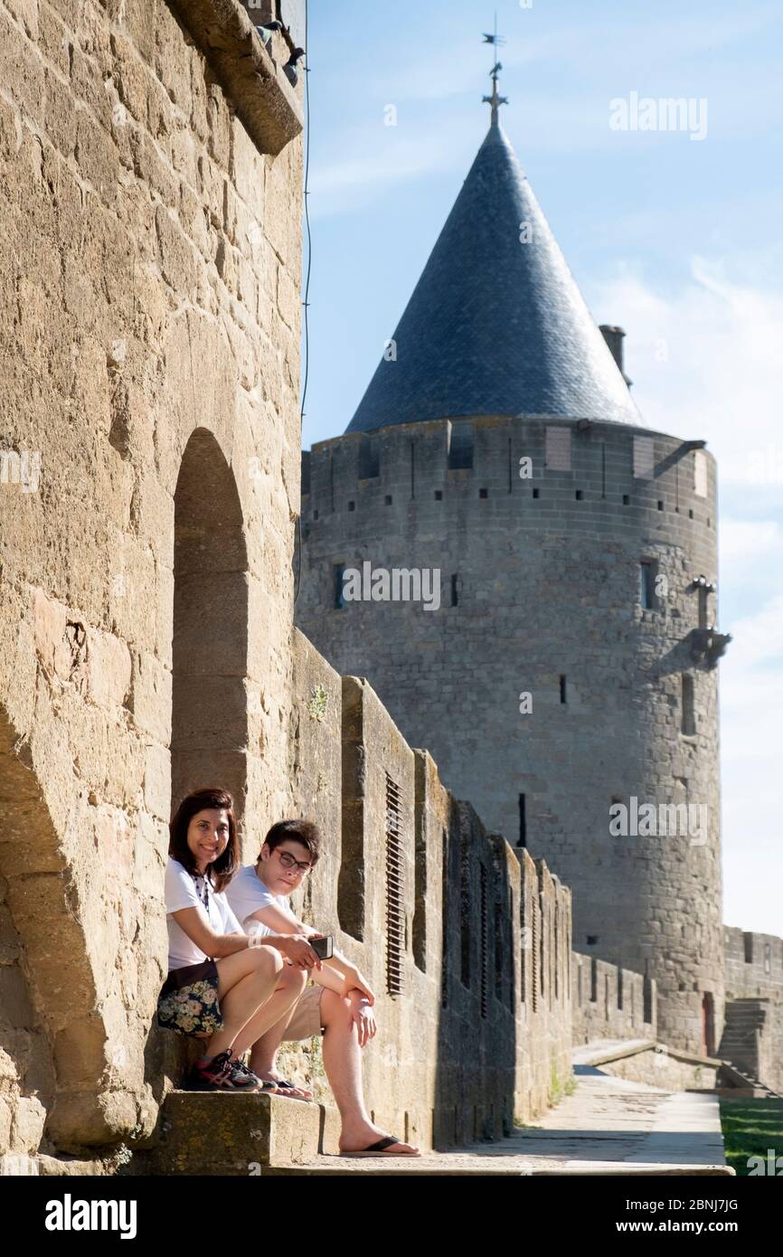 Mutter und Sohn im Urlaub und sitzen vor der Hauptmauer des mittelalterlichen Schlosses, Carcassonne, UNESCO-Weltkulturerbe, Aude, Languedoc, Frankreich, Stockfoto
