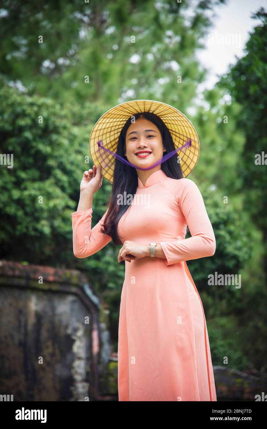 Porträt einer jungen Vietnamesin in einem Ao Dai Kleid und konischen Hut in einem buddhistischen Tempel, Hue, Vietnam, Indochina, Südostasien, Asien Stockfoto