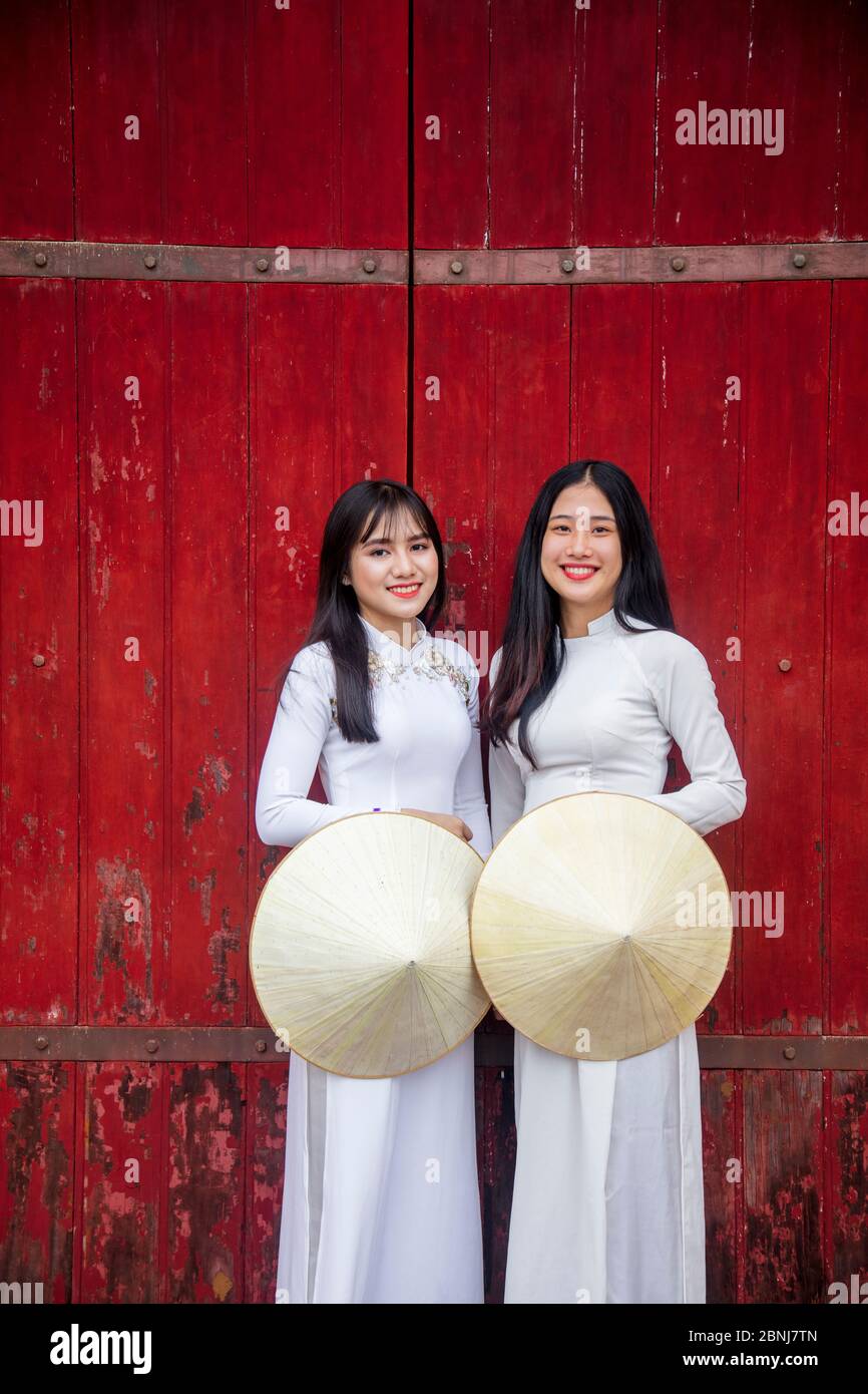 Zwei junge Frauen in traditioneller Kleidung stehen am westlichen Tor zur Purple Forbidden City, Hue, Vietnam, Indochina, Südostasien, Asien Stockfoto