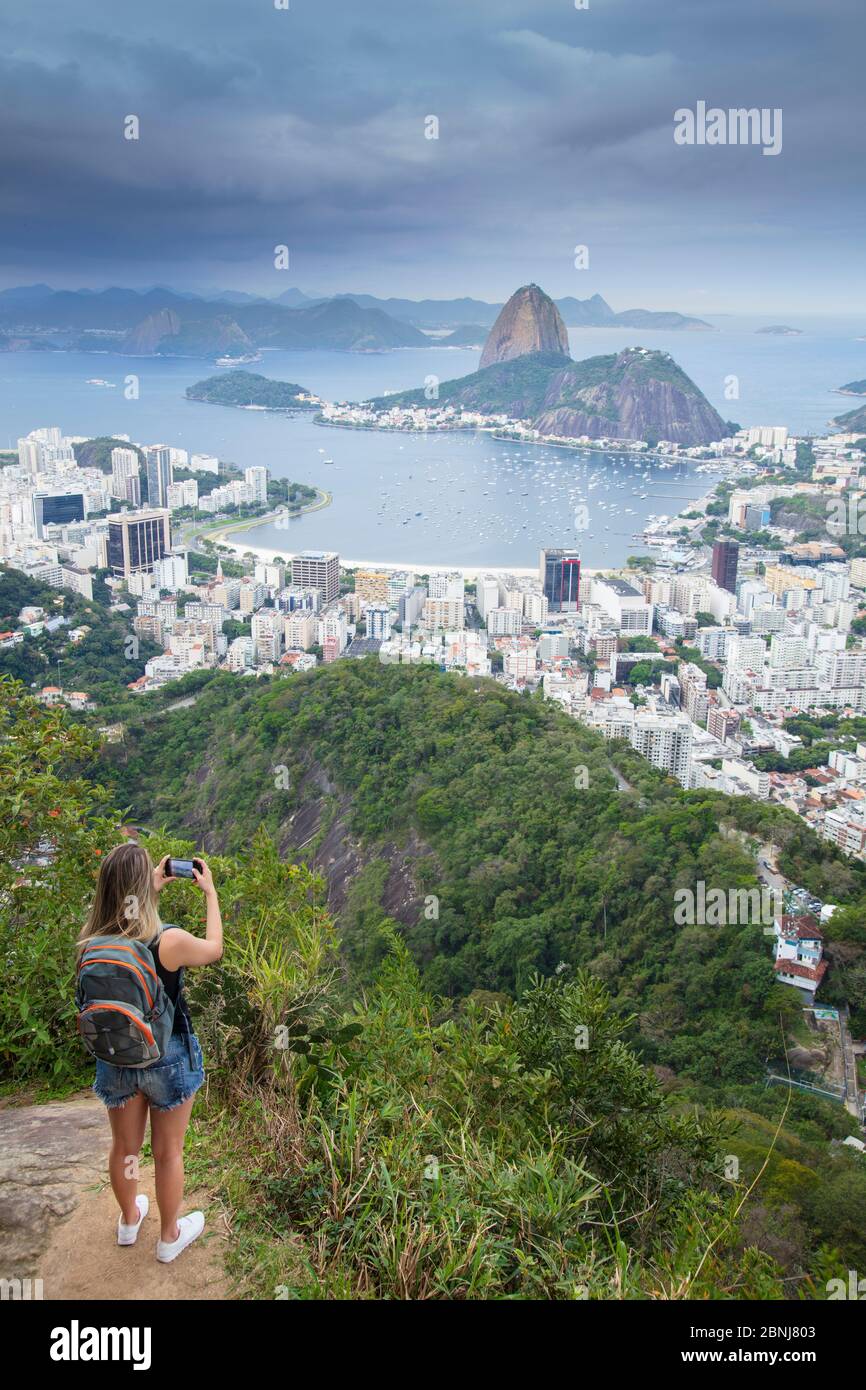 Eine Wanderin mit Blick auf die Landschaft von Rio zum Zuckerhut Berg vom Tijuca Nationalpark, Rio de Janeiro, Brasilien, Südamerika Stockfoto
