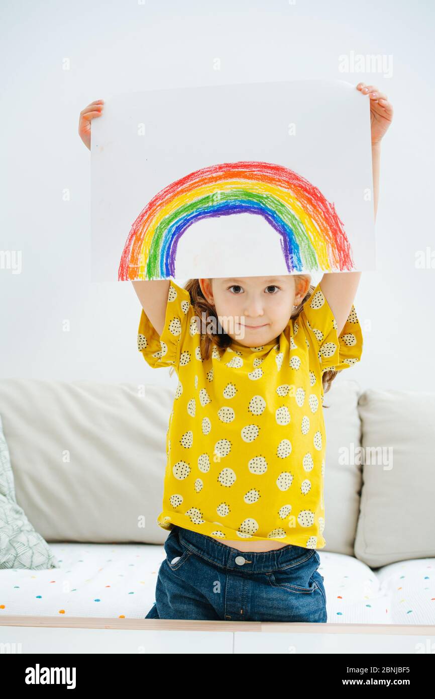 Kleines Mädchen mit einem Regenbogen, den sie gerade über ihrem Kopf gemalt hat Stockfoto