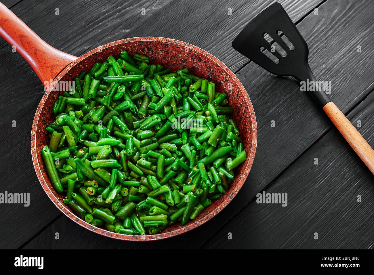 Vegetarisches Essen. Gebratene Bohnen in einer Pfanne. Stilvoller Hintergrund für Design. Minimalismus. Gesunde Lebensmittel aus Gemüse. Stockfoto
