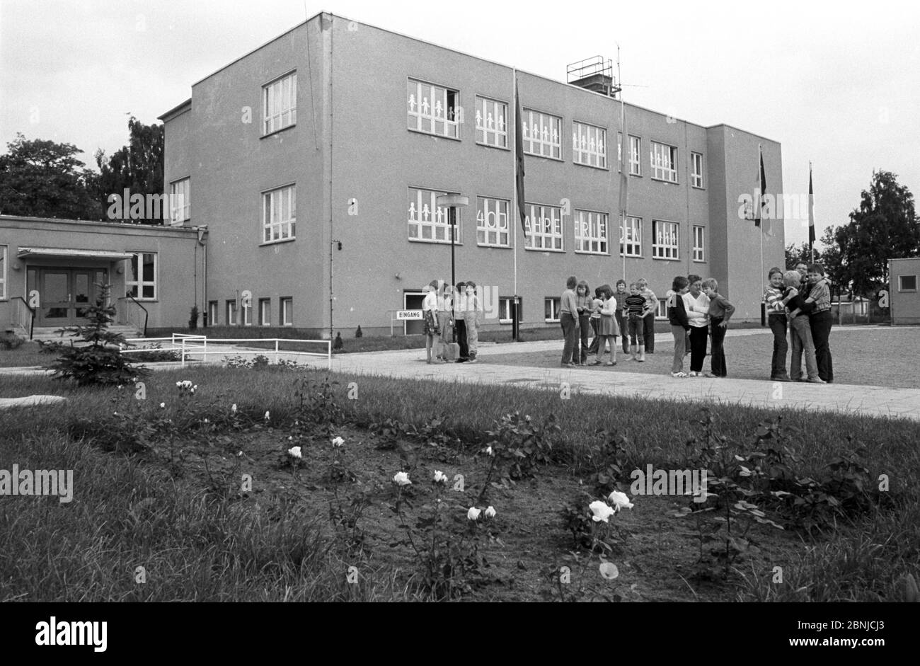 30. November 1984, Sachsen, Arzberg: Ende der 1980er Jahre stehen die Schüler vor dem Neubau der Heinrich-Rau-Oberschule in Arzberg (bei Torgau). In den Schulfenstern heißt es in den Großbuchstaben: "40 Jahre Frieden". Das genaue Datum der Aufnahme ist nicht bekannt. Foto: Volkmar Heinz/dpa-Zentralbild/ZB Stockfoto
