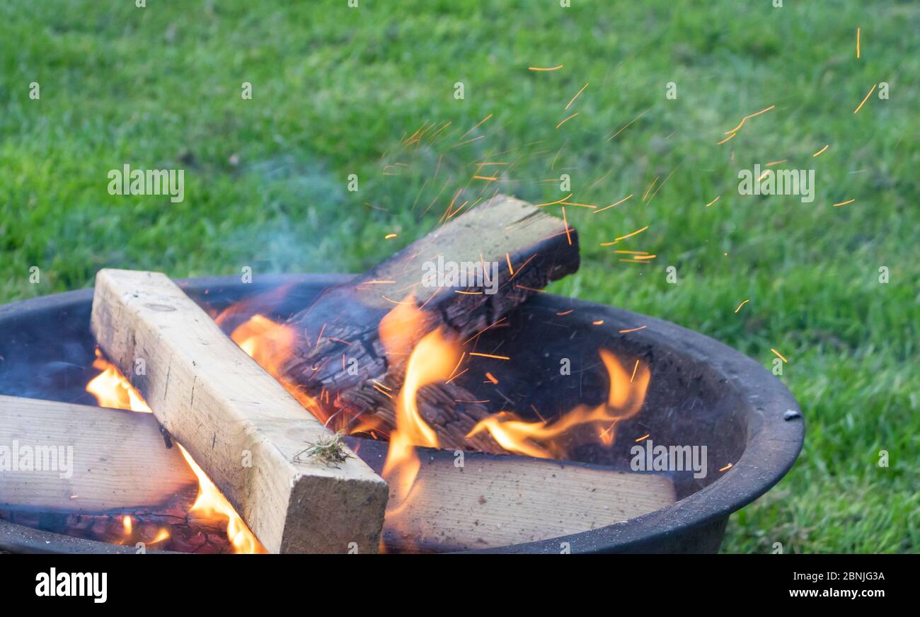 Ein knisterndes Feuer bricht sanft mit Funken aus einer bescheidenen Feuergrube Stockfoto