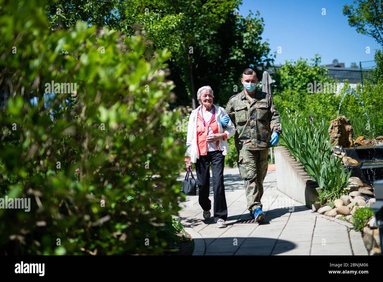 Solingen, Deutschland. Mai 2020. Ein Bewohner geht mit einem Soldaten im Garten des Elisabeth Roock Hauses. 6 Soldaten des Aufklärungsbataillons 7 aus Ahlen unterstützen im Rahmen der Verwaltungshilfe Pflegekräfte im Seniorenheim Elisabeth-Roock-Haus. Quelle: Jonas Güttler/dpa/Alamy Live News Stockfoto