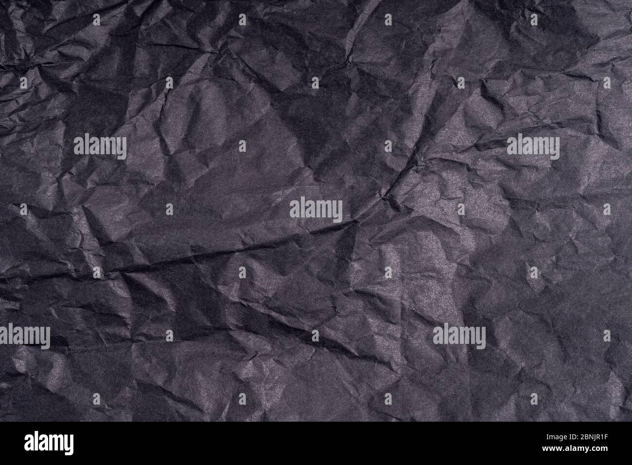 Dunkle zerknitterte gefaltet schwarzen Papier Poster Textur. Unbeschriftete zerknitterte, körnige Papieroberfläche. Verschmierter, munziger Karton mit Faser. Nahaufnahme. Stockfoto