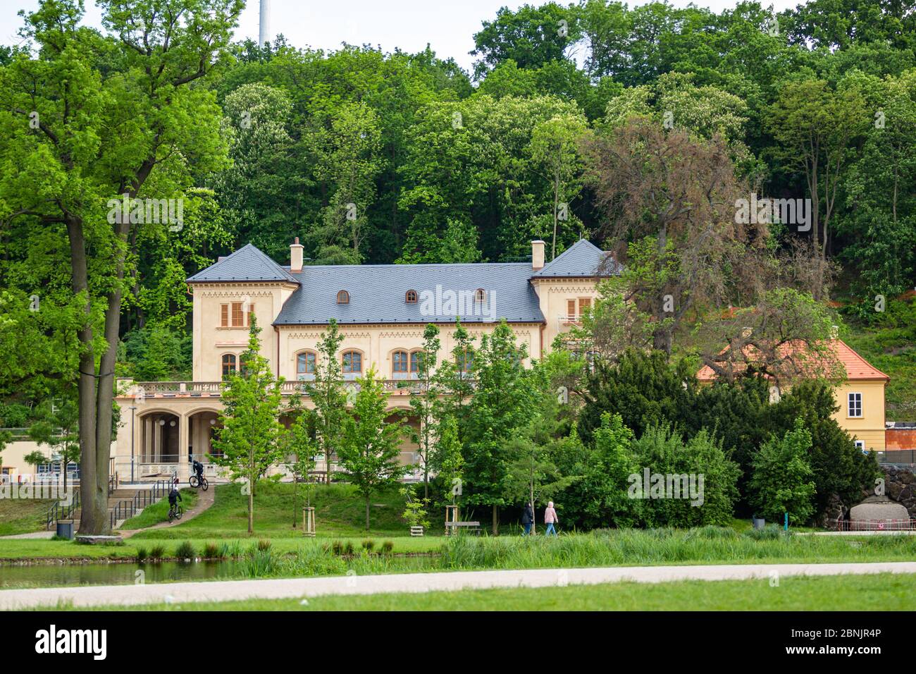 Prag, Tschechische Republik - Mai 14 2020: Blick auf das Restaurant Slechtova nach der Renovierung über einen Park mit grünen Rasen und Bäumen. Sonniger Frühlingstag. Stockfoto