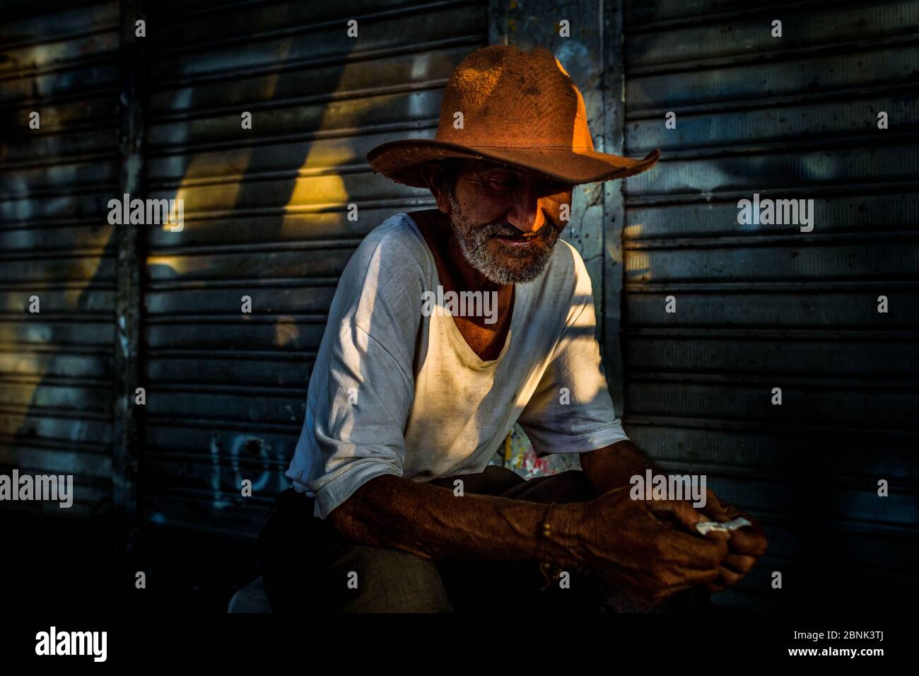Ein kolumbianischer Verkäufer, der einen Cowboyhut trägt, versteckt sich im Schatten auf dem Plaza Minorista Markt in Medellín, Kolumbien. Stockfoto