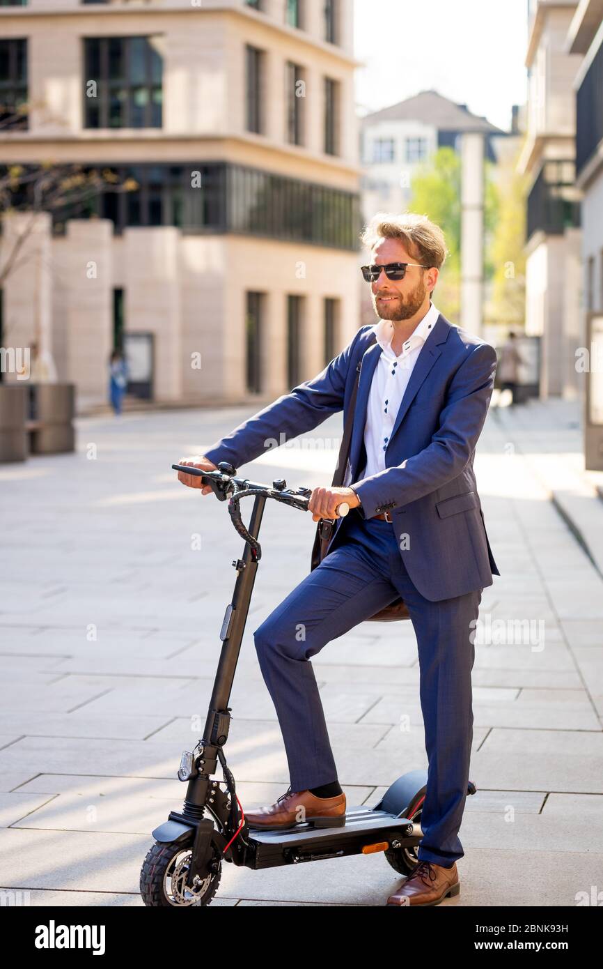 Mann im Anzug auf einem E-Scooter Stockfoto