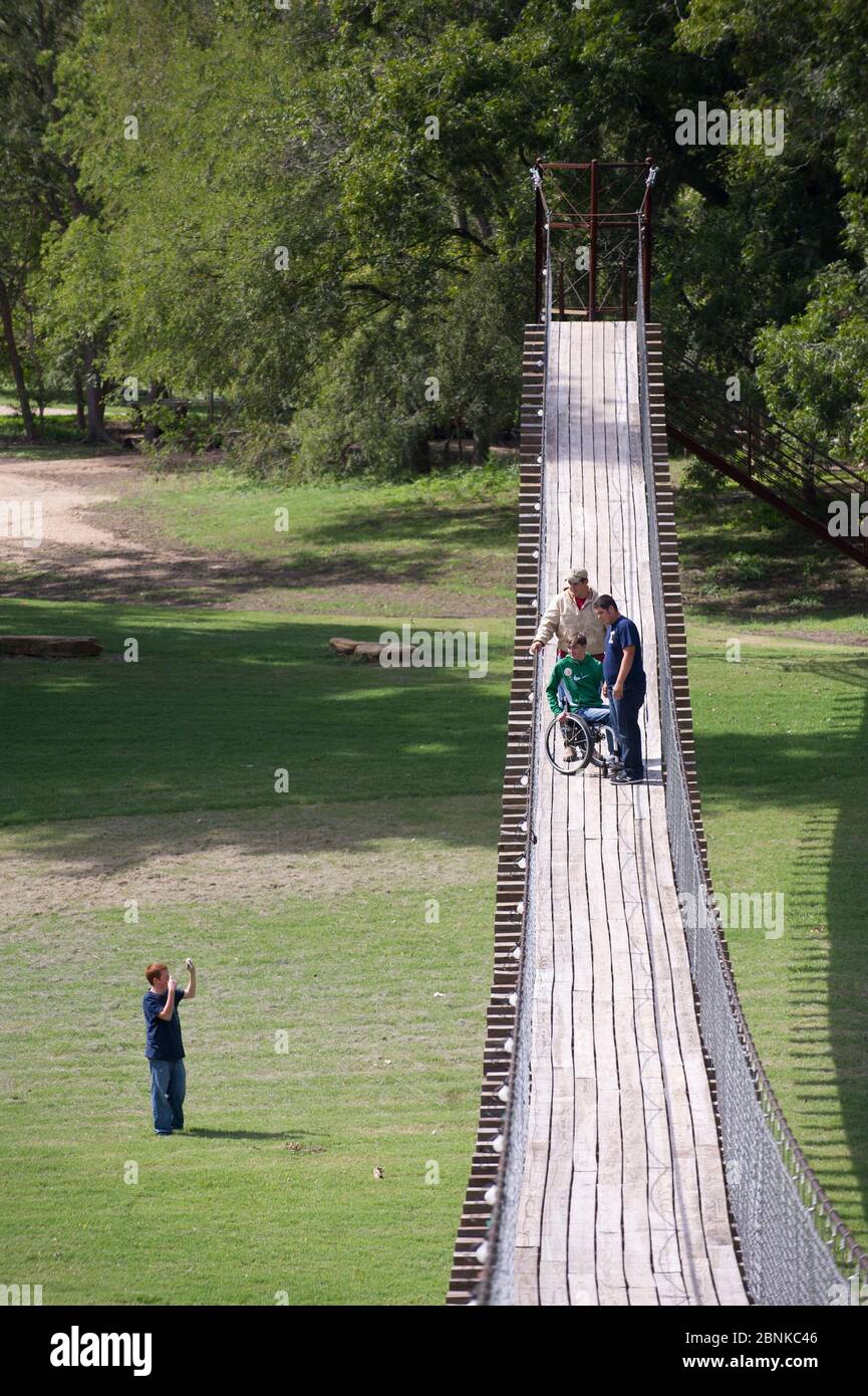 Apache Pass Texas, USA, 2012. Oktober: Der Junior High Studentin Rollstuhl überquert eine schwingende Brücke über den San Gabriel River in Zentral-Texas während eines Exkurses, um die Widmung bei der Enthüllung des ersten Straßenschilds entlang des texanischen Teils des El Camino Real del los Tejas National Historic Trail am Apache Pass zu besuchen. ©Bob Daemmrich Stockfoto