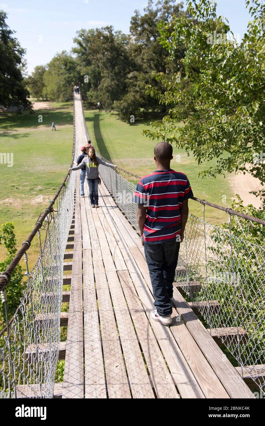 Apache Pass Texas, USA, 2012. Oktober: Der Junior High Studentin Rollstuhl überquert eine schwingende Brücke über den San Gabriel River in Zentral-Texas während eines Exkurses, um die Widmung bei der Enthüllung des ersten Straßenschilds entlang des texanischen Teils des El Camino Real del los Tejas National Historic Trail am Apache Pass zu besuchen. ©Bob Daemmrich Stockfoto