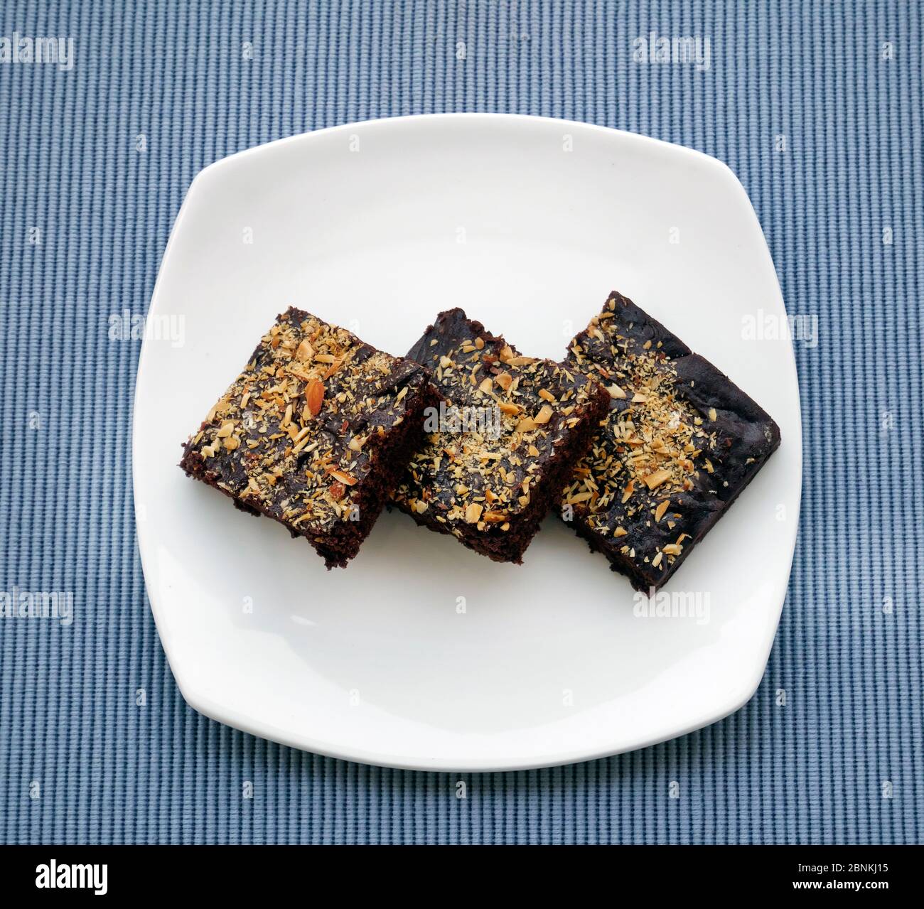 BROWNIES IN EINEM WEISSEN TELLER, GARNIERT MIT GERÖSTETEN MANDELN Stockfoto