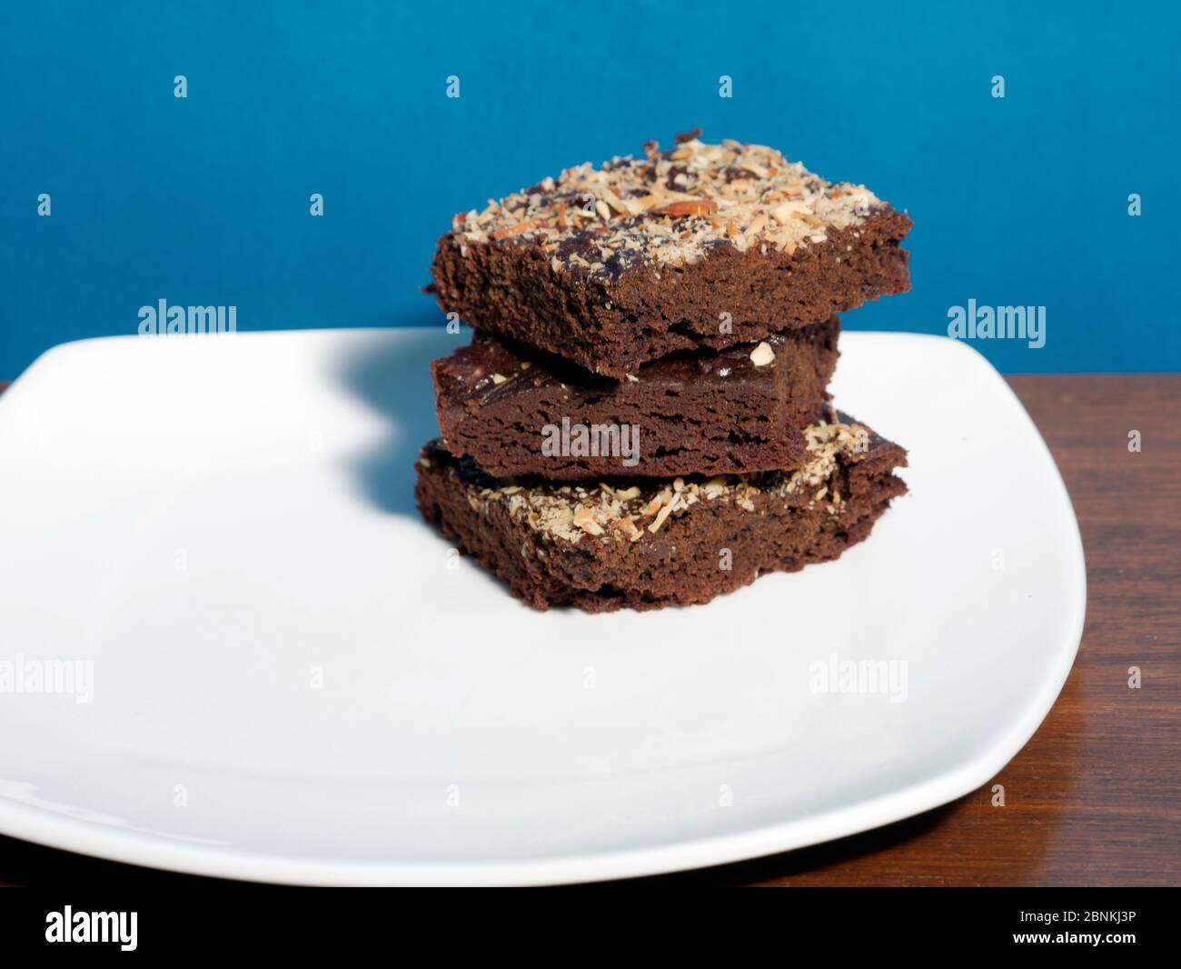 BROWNIES IN EINEM WEISSEN TELLER, GARNIERT MIT GERÖSTETEN MANDELN Stockfoto