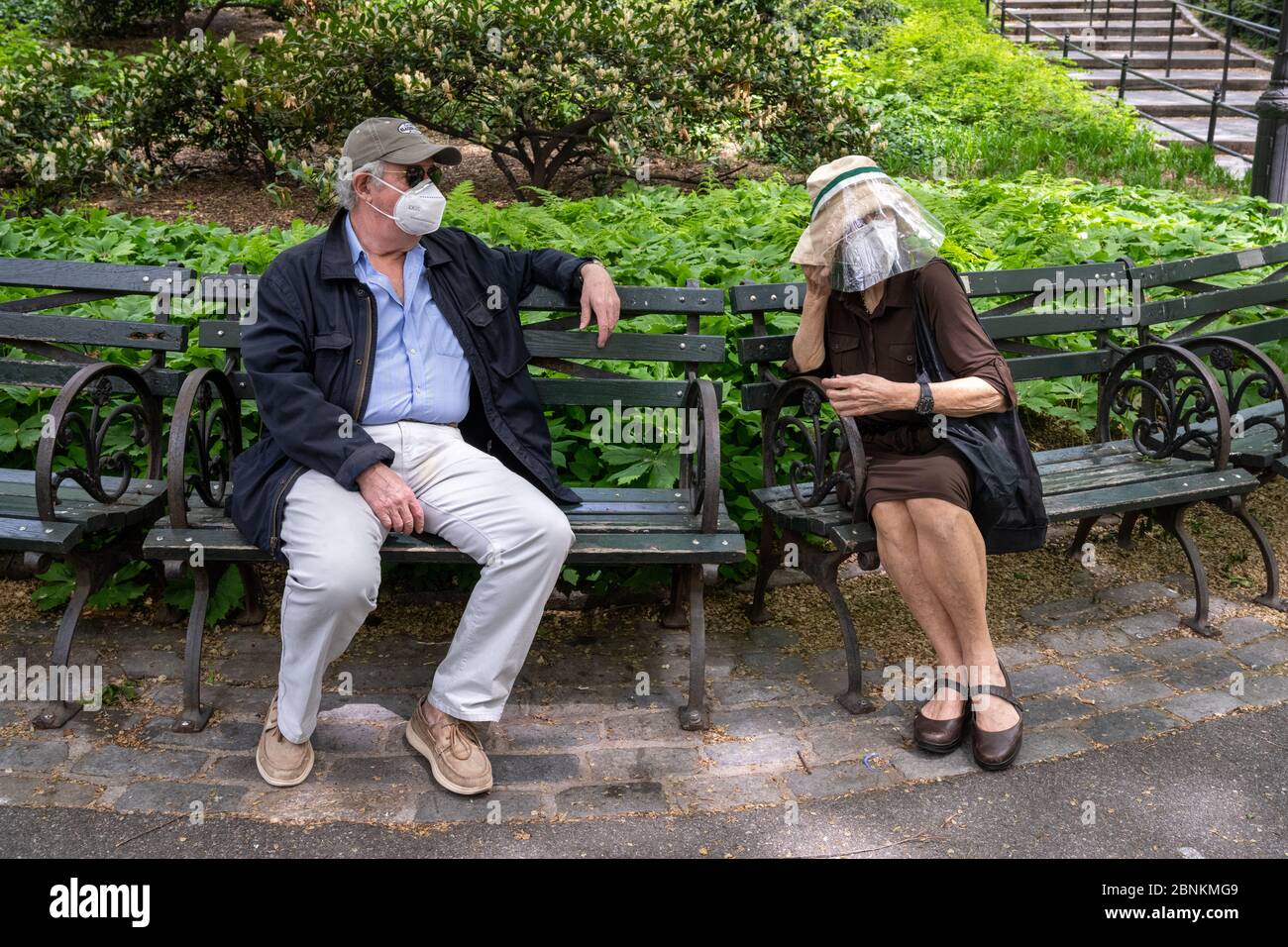 New York, USA. Mai 2020. Ein Paar, das Gesichtsmasken und Schutzvorrichtungen trägt, behält soziale Distanz, während sie während der Coronavirus-Krise im Central Park sitzen. Kredit: Enrique Shore/Alamy Live News Stockfoto