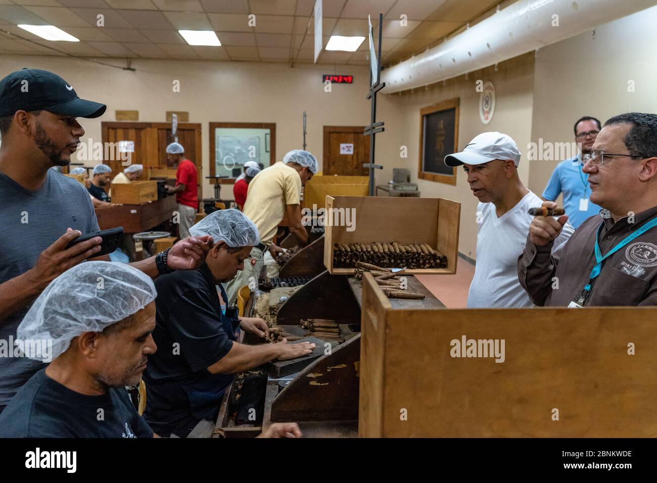 Karibik, Großantillen, Dominikanische Republik, Santiago, Teilnehmer einer Fabrikführung beobachten den Zigarrenroller in der Zigarrenfabrik La Aurora Stockfoto