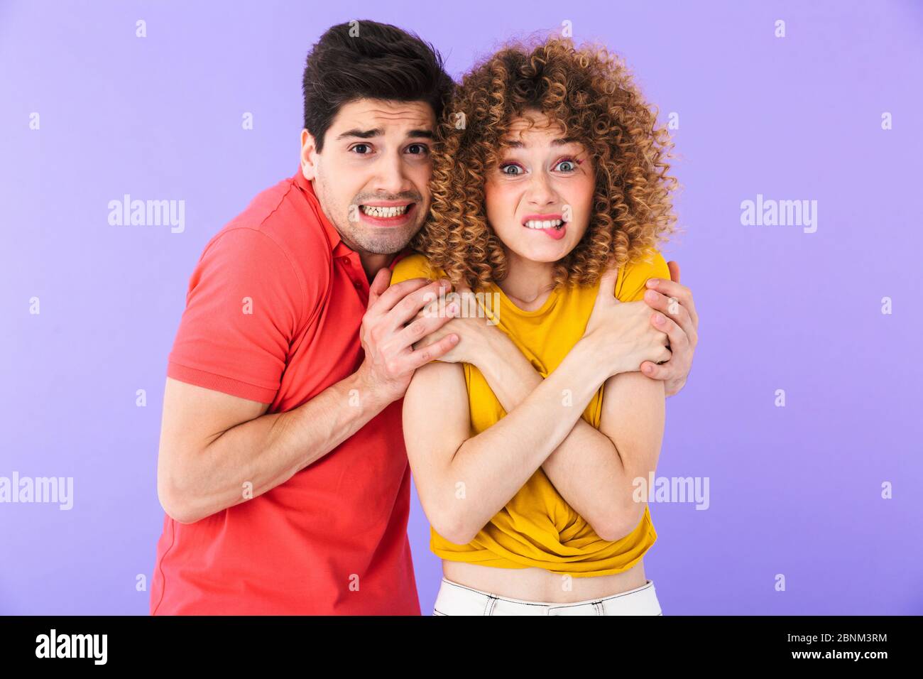 Porträt von verworrenen gefrorenen kaukasischen Menschen Mann und Frau tragen T-Shirts zittern und Zittern von Kälte isoliert auf violettem Hintergrund Stockfoto