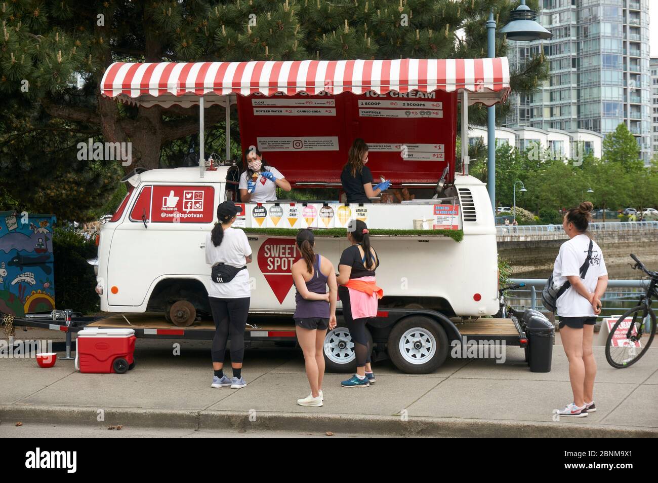 Eine Frau mit einer Schutzmaske serviert Kunden Eis von einem Food Truck in Vancouver, BC, Kanada Stockfoto