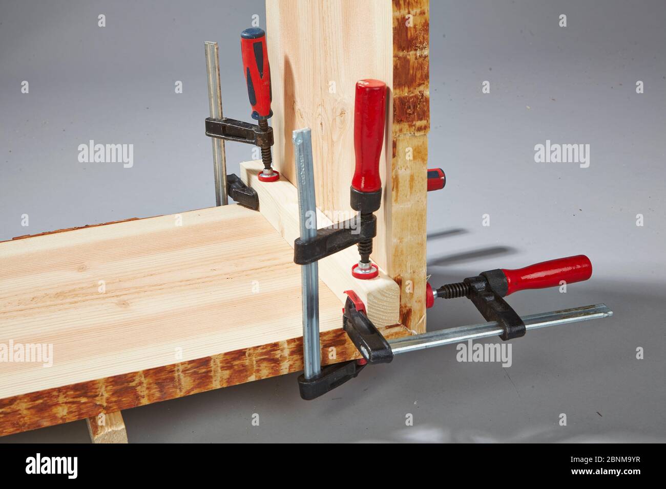 Bau eines Holzregals, Do-it-yourself-Produktion, Schritt für Schritt, Schritt 8 Stabilisierung der Frischklebung mit Hilfe von Schraubklemmen und einer Hilfsschiene, die nach dem Aushärten entfernt wird. Stockfoto