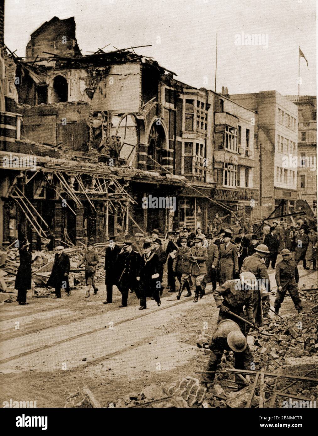WWII - EIN gedrucktes Bild von 1941, das den Zweiten Weltkrieg zeigt, wie König George Southampton, England nach dem großen Bombenangriff vom 30. November 1940 besucht, während Truppen weiterhin die Straßen von Schutt und Asche räumen. Stockfoto