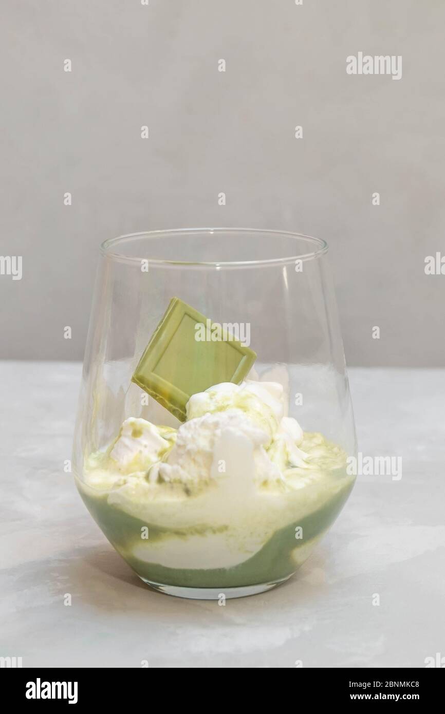 Matcha Affogato Dessert. Kugeln Vanilleeis mit Matcha-Tee in einer Glasschale auf neutralem Hintergrund Stockfoto