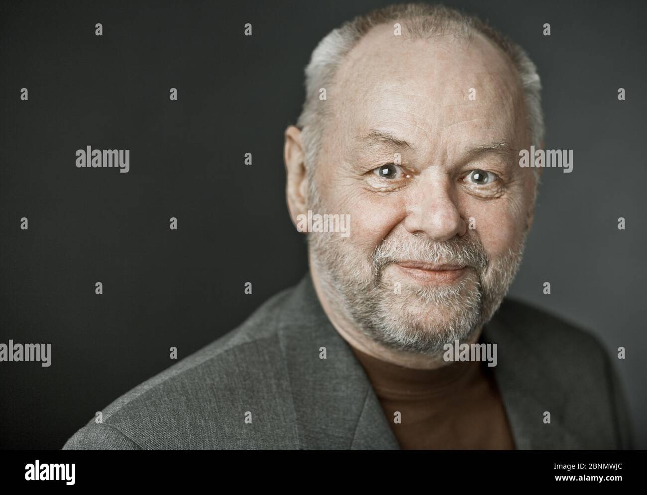 Älterer Mann mit Bart und Glatze schaut glücklich auf die Kamera Stockfoto