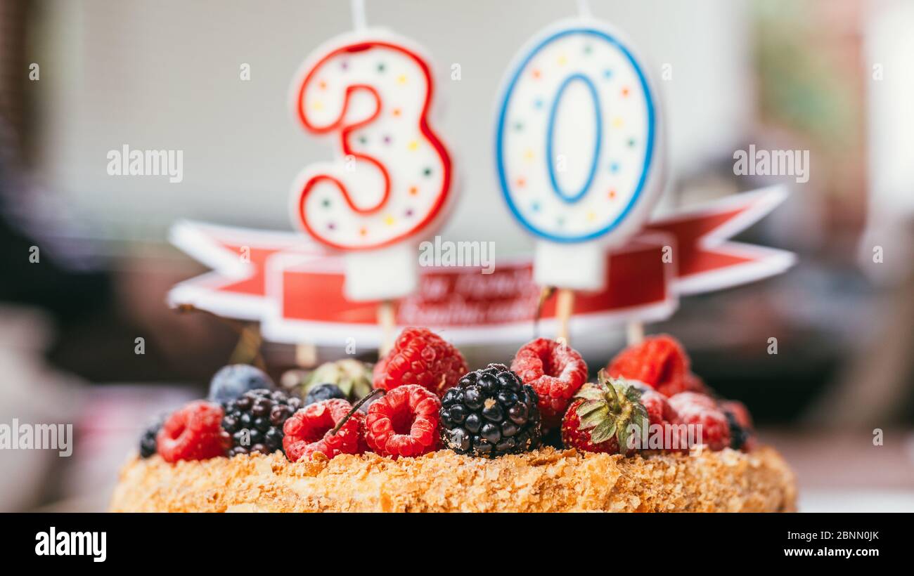 Himbeeren Brombeere Geburtstagstorte mit Kerzen Nummer 30 auf entkochten Hintergrund. Makroaufnahme mit selektivem Fokus und flachem Freiheitsgrad Stockfoto