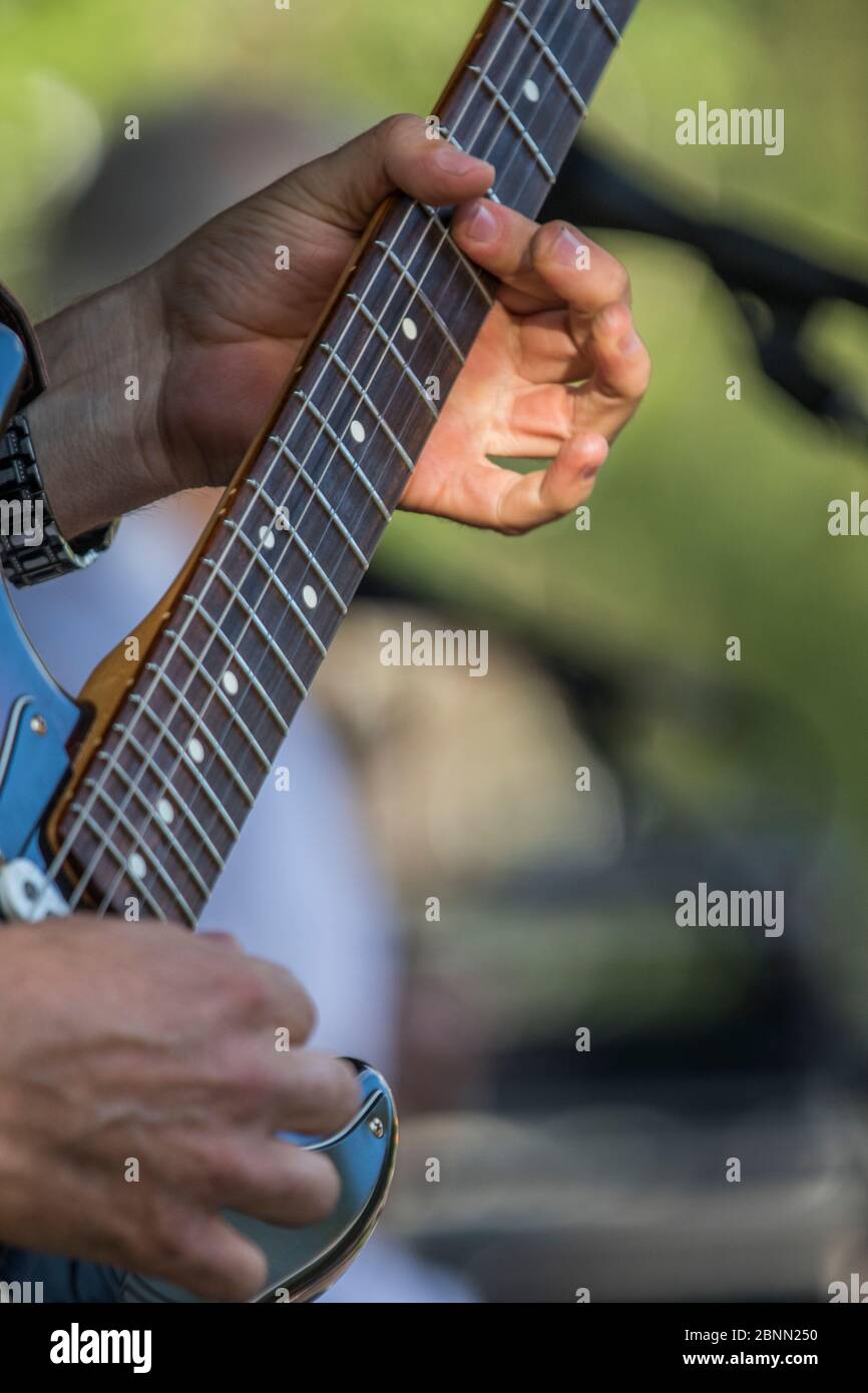 Scharf gekleideter Musiker, spielt einen Fender Statocaster, singt und im Outdoor-Konzert. Stockfoto