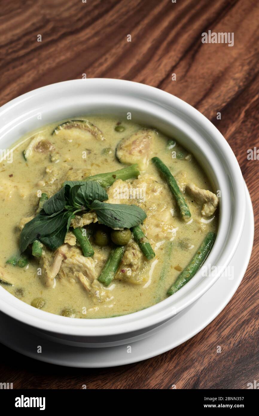 thailändisches grünes Curry mit Huhn und Gemüse auf Holztisch Stockfoto