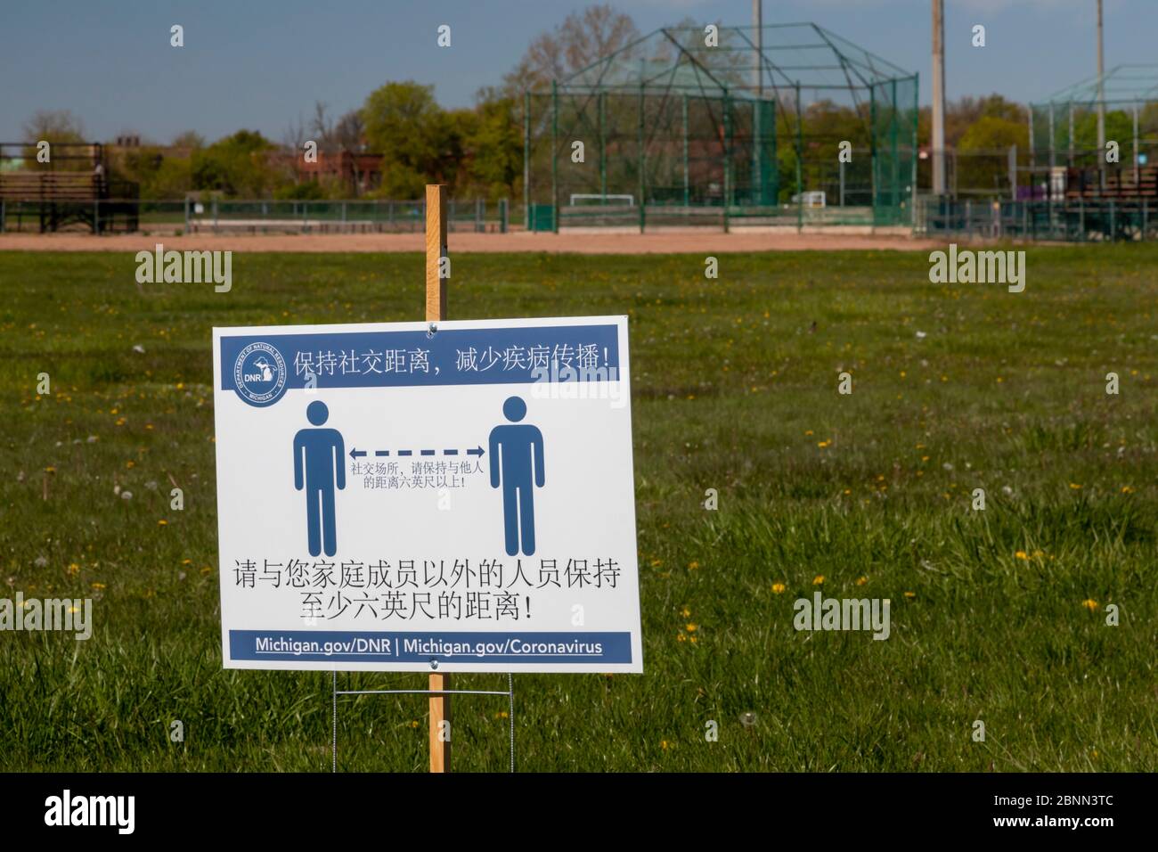 Detroit, Michigan - Schilder in mehreren Sprachen auf einem Softballfeld im Belle Isle State Park erinnern Besucher daran, die richtige soziale Distanz A zu bleiben Stockfoto