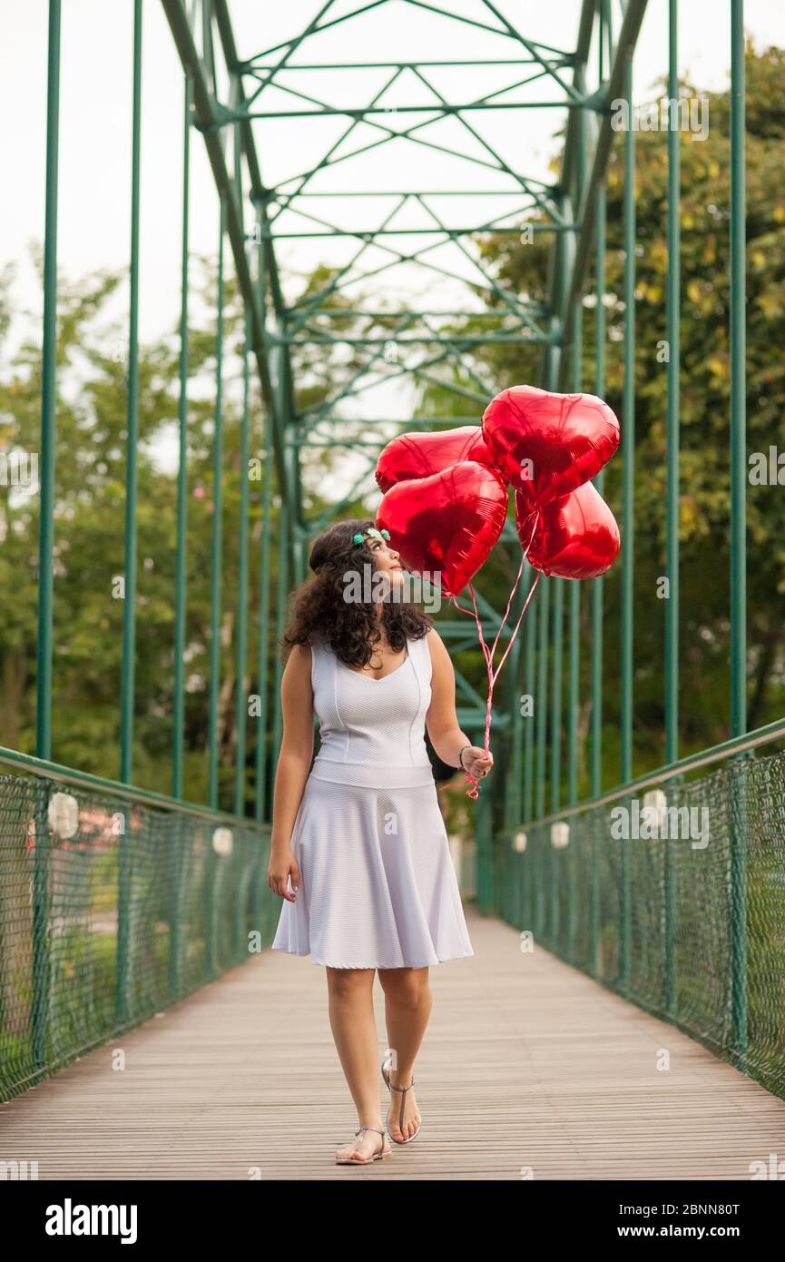 Romantische Szene. Mädchen zu Fuß im Park tragen rote Ballons in Herzform. Stockfoto