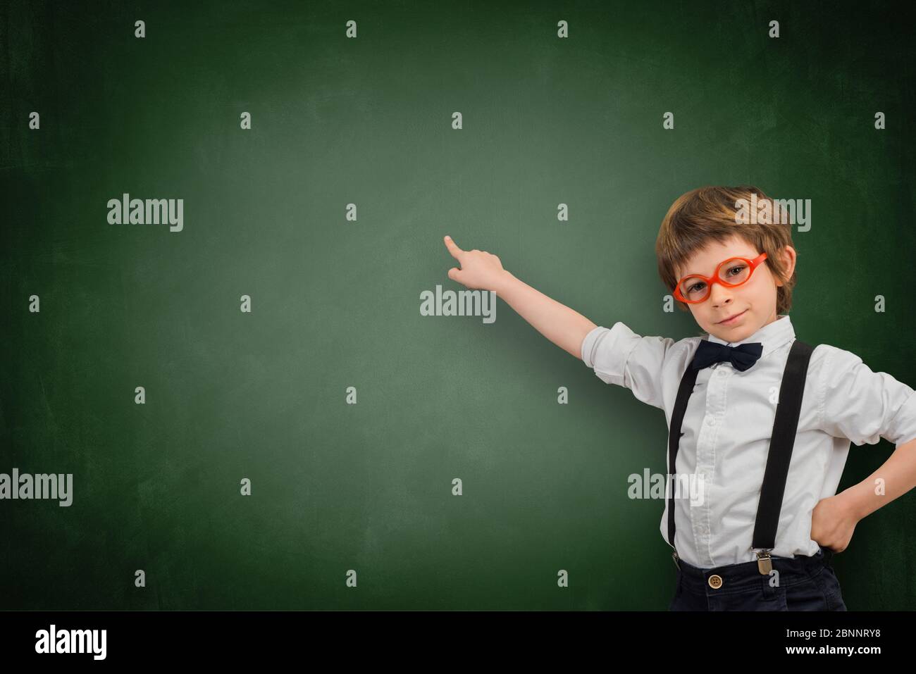 Der Junge zeigt mit dem Finger auf eine leere Tafel Stockfoto