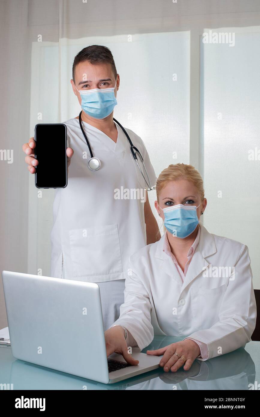 Ein paar Ärzte mit Geräten zeigen einen leeren Smartphone-Bildschirm Stockfoto
