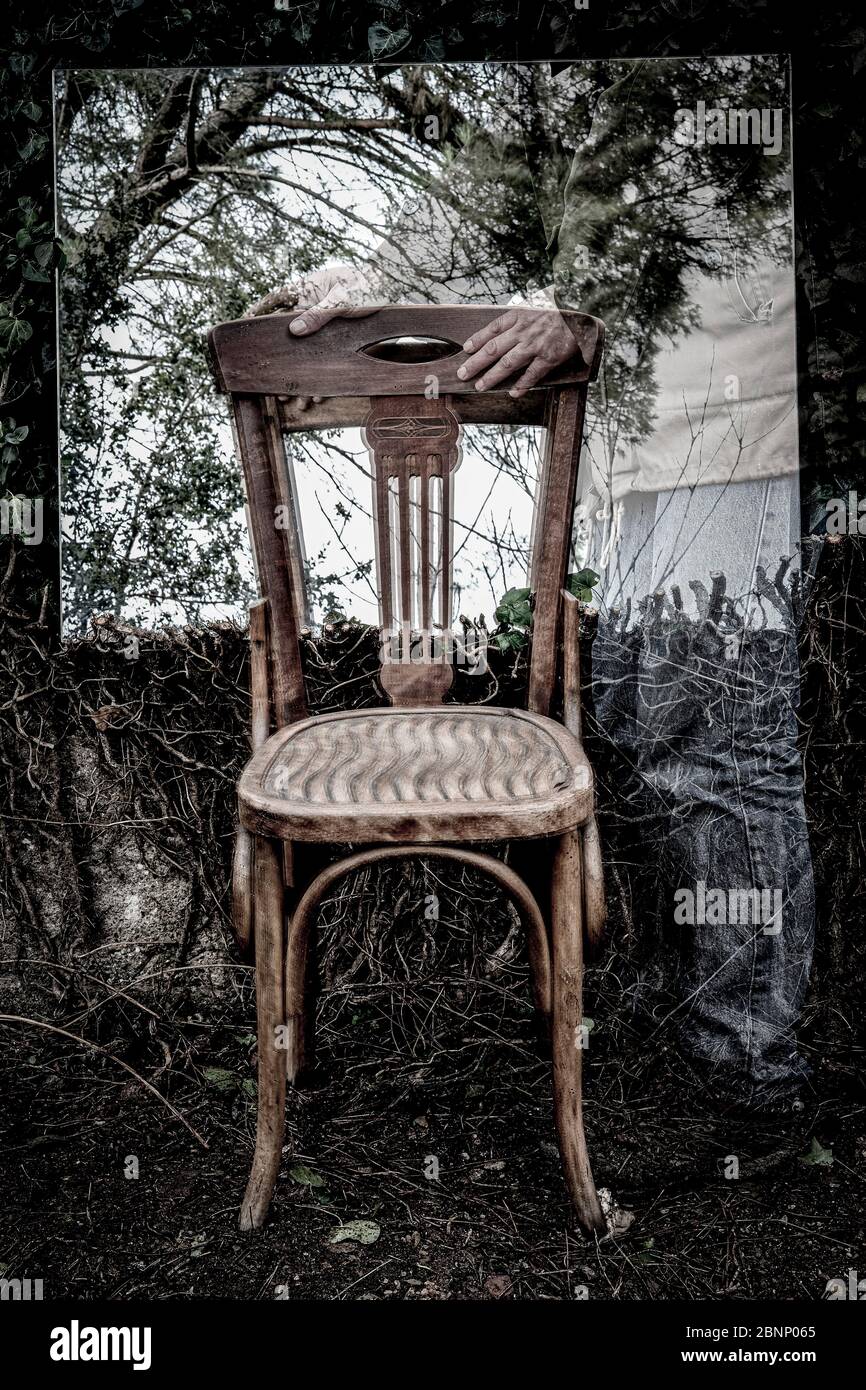 Poetisches Bild von Reflexionen in einem Garten und Wald mit einem Holzstuhl in einer Atmosphäre eines Traums Stockfoto