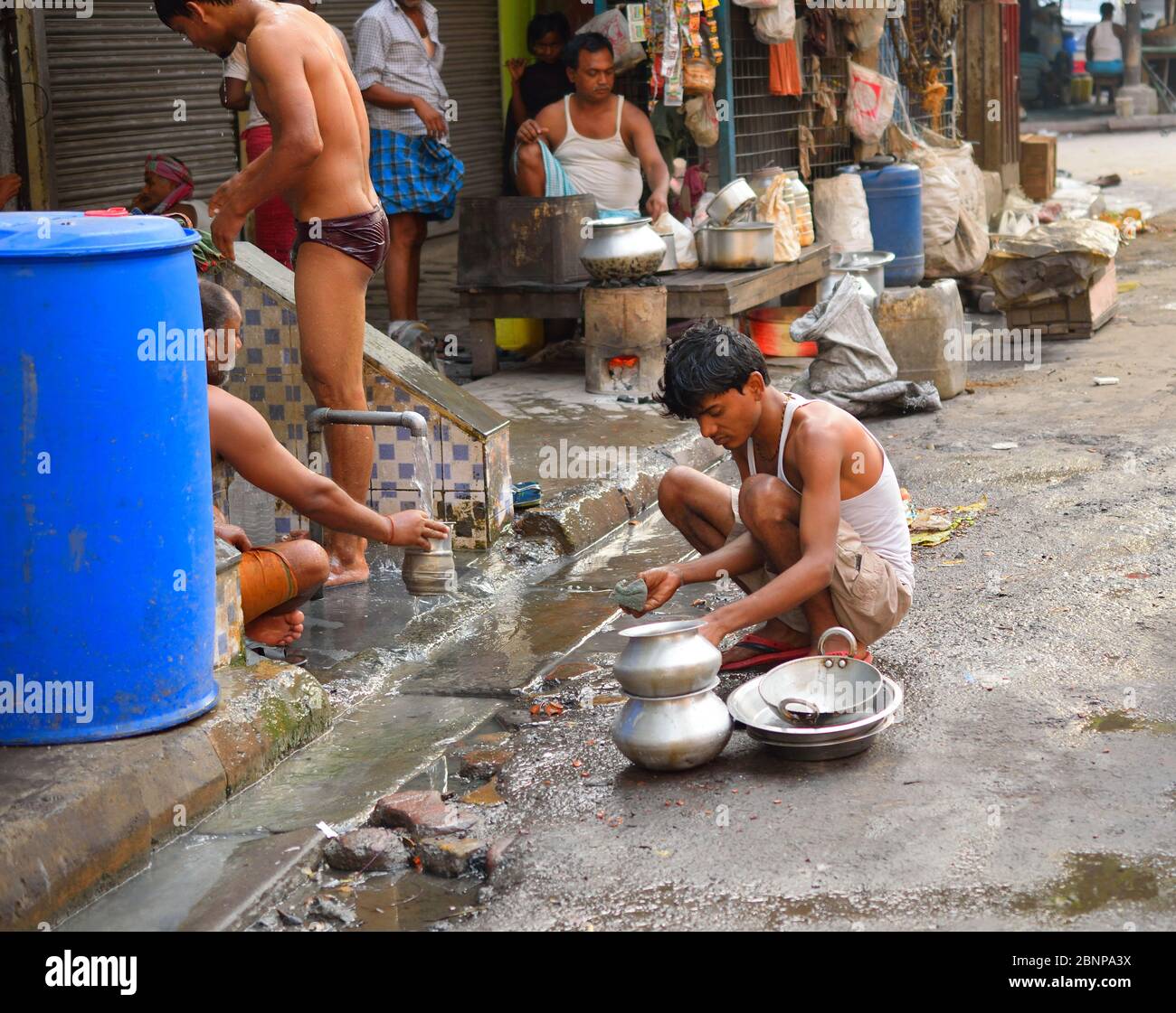 Ein Mann, der Utensilien am Straßenrand wäscht Stockfoto