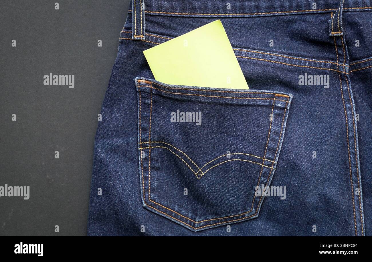 Leeres gelbes Papier, das aus der Denim-Jeans-Tasche herausgeklebt wurde. Platz für Text. Stockfoto