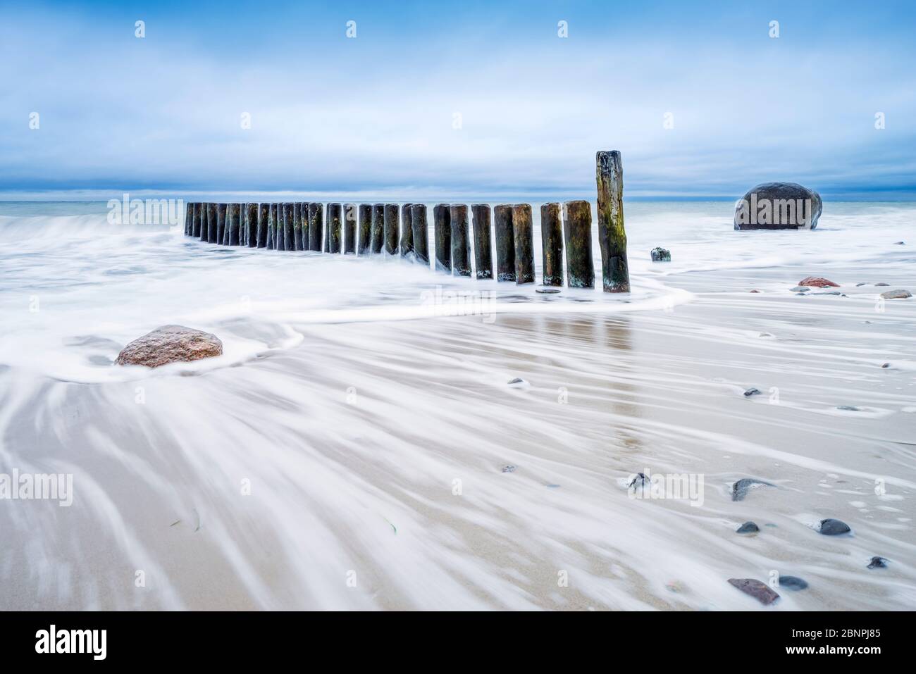 Groyne und Felsbrocken am Ostseestrand, wolkiger Himmel, stürmisches Meer, bei Rostock, Mecklenburg-Vorpommern, Deutschland Stockfoto