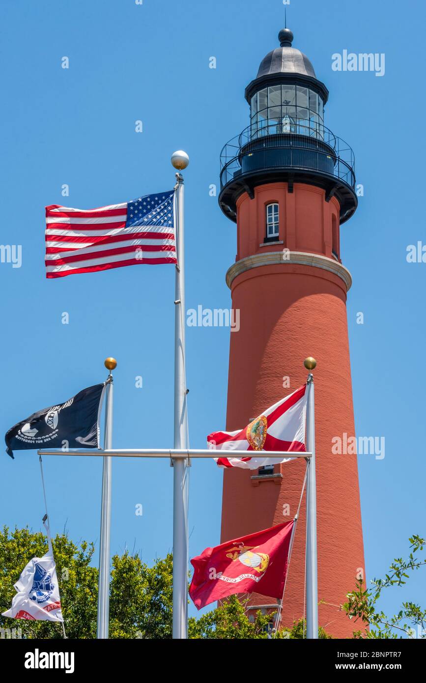 Historischer Leuchtturm Ponce Inlet, fertiggestellt 1887, in Ponce Inlet, Florida, mit Fahnen wehend unten am Ponce Inlet Veterans Memorial. (USA) Stockfoto Historischer Leuchtturm Ponce Inlet, fertiggestellt 1887, in Ponce Inlet, Florida, mit Fahnen wehend unten am Ponce Inlet Veterans Memorial. (USA) Stockfoto