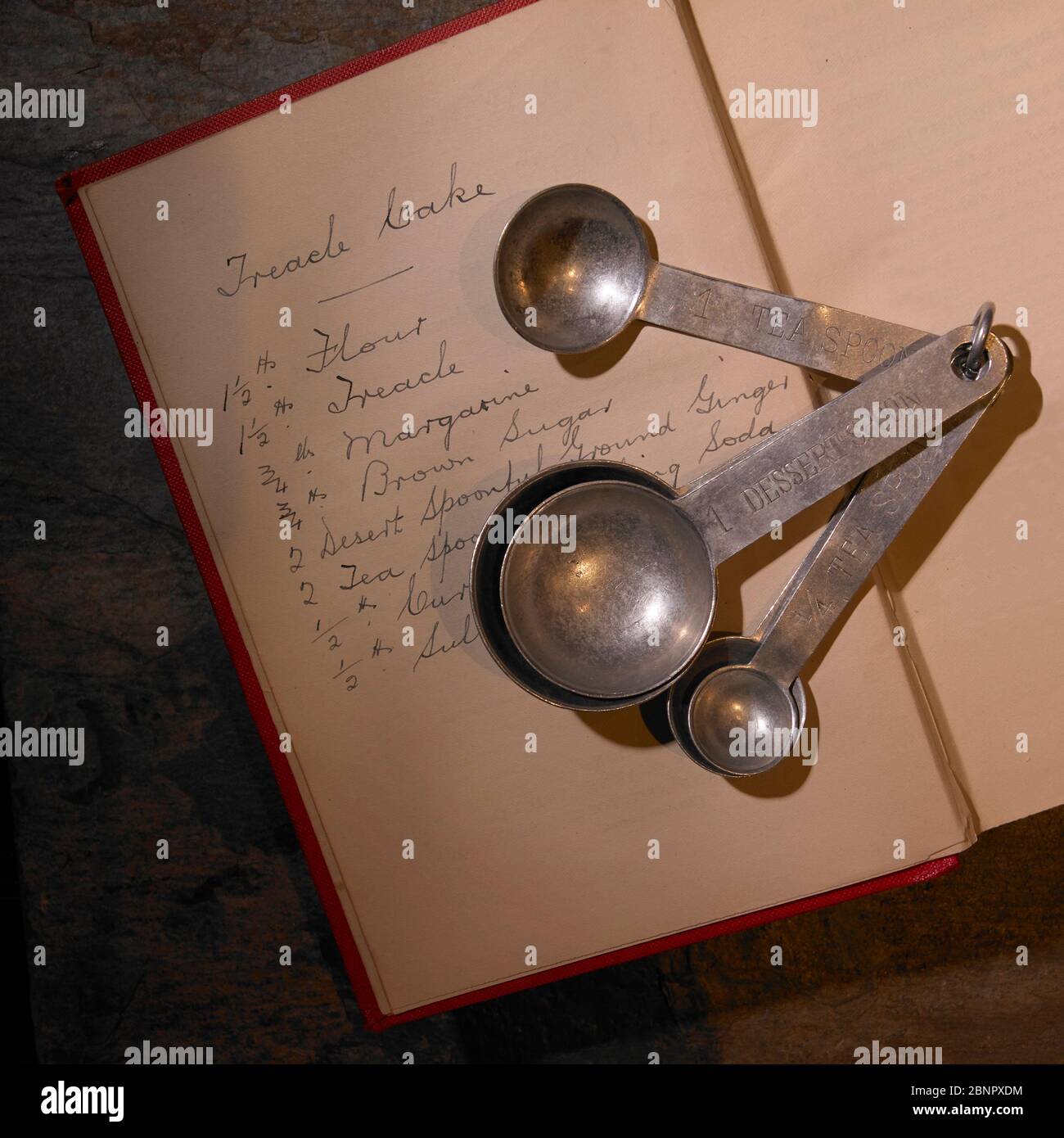 Kaiserliche Maßnahme Löffel liegen auf der Vorderseite des 19.-frühen 20. Jahrhundert Rezeptbuch mit handgeschriebenen Treacle Cake Rezept komplett mit Maßnahmen. Stockfoto