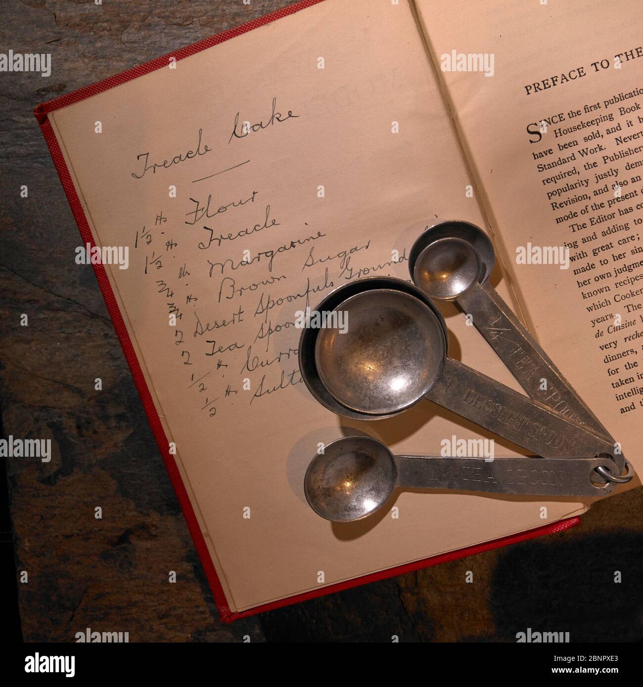 Kaiserliche Maßnahme Löffel liegen auf der Vorderseite des 19.-frühen 20. Jahrhundert Rezeptbuch mit handgeschriebenen Treacle Cake Rezept komplett mit Maßnahmen. Stockfoto