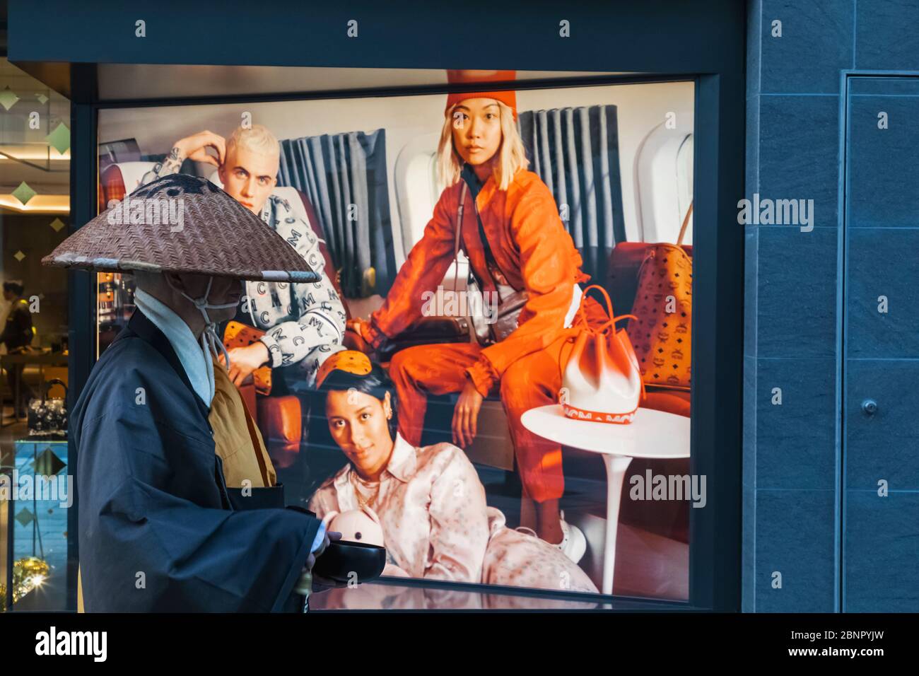 Japan, Honshu, Tokio, Ginza, Chuo-dori Shopping Street, Monk Walking vor dem Clothing Store Window Display Stockfoto