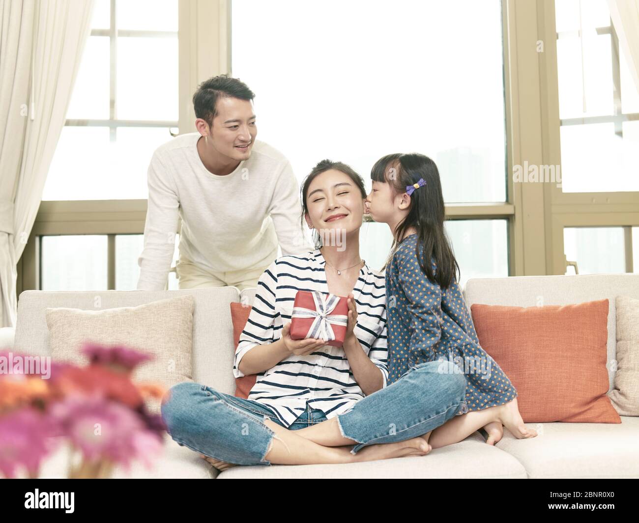Wenig asiatisch gilr Tochter küssen Mutter auf die Wange nach dem Geben ein Geschenk Stockfoto