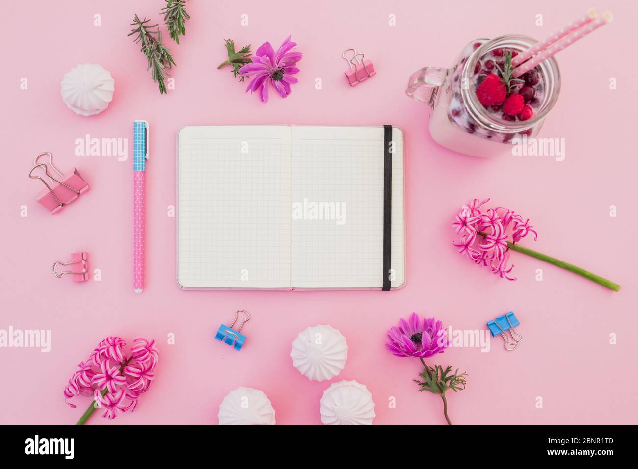 Beeren Smoothie mit Strohhalmen, Marshmallow, Tagebuch, Stift und rosa Blüten auf rosa. Flaches Lay. Draufsicht Stockfoto
