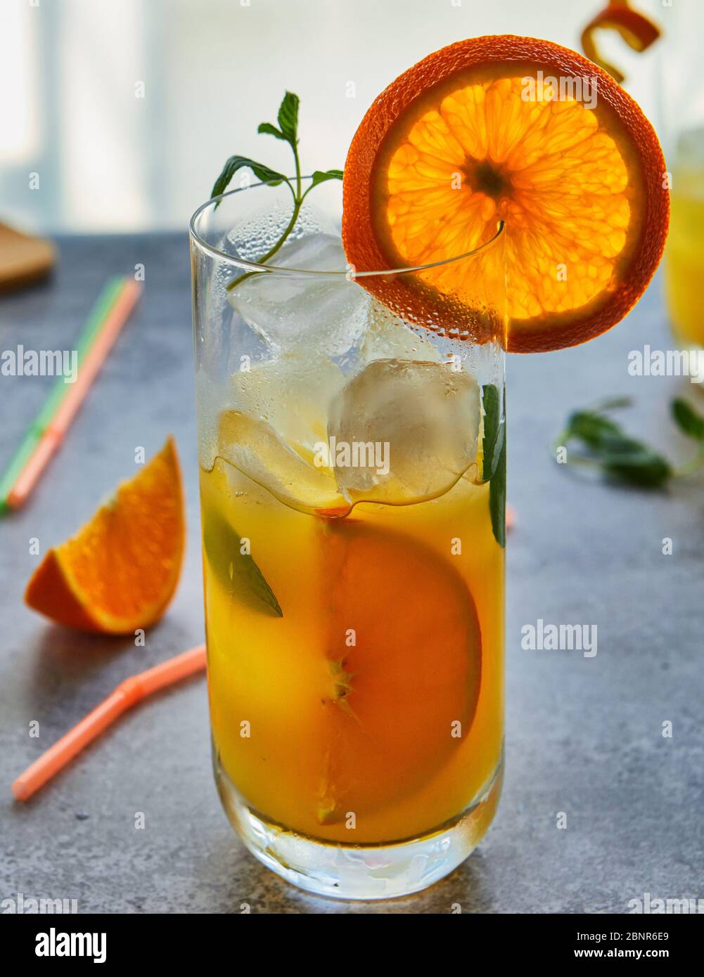 Foto von frischem Orangensaft im Glasgefäß. Sommer gesundes Bio-Getränk Konzept. Kalte Getränke mit Eis und Orangenfrüchten. Stockfoto