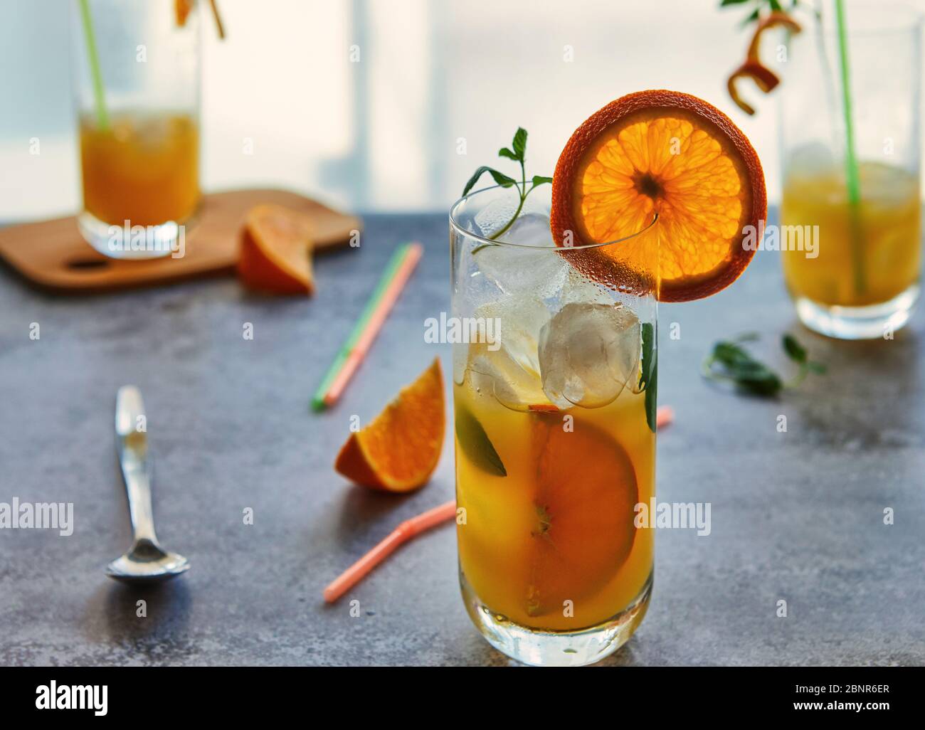 Foto von frischem Orangensaft im Glasgefäß. Sommer gesundes Bio-Getränk Konzept. Kalte Getränke mit Eis und Orangenfrüchten. Stockfoto